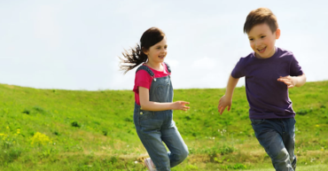 dečak i devojčica trče po livadi